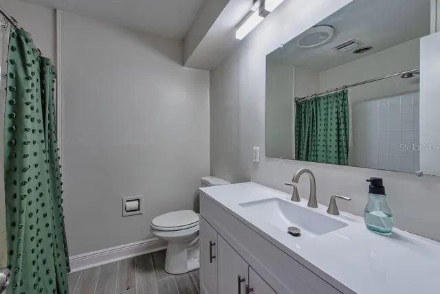 a bathroom with a granite countertop toilet a sink and a mirror