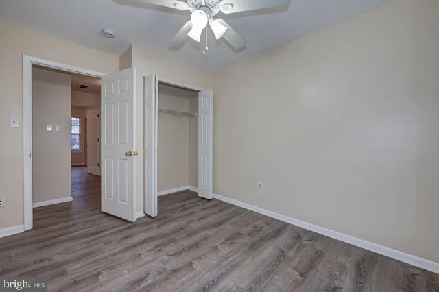 an empty room with wooden floor and ceiling fan