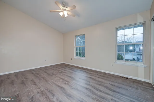 a view of empty room with wooden floor and fan