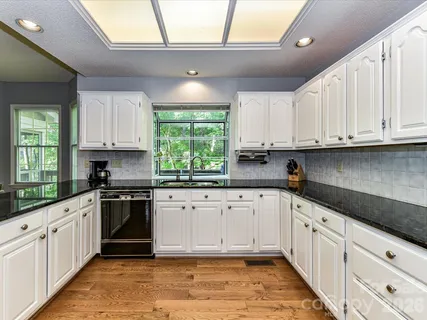 a white kitchen with granite top and stainless steel appliances