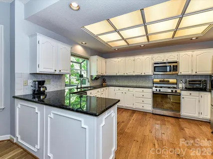 a kitchen with stainless steel appliances granite countertop a sink window and cabinets