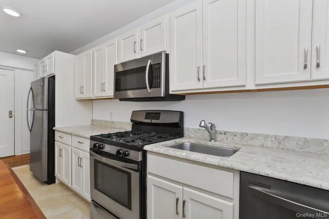 a kitchen with granite countertop white cabinets and stainless steel appliances