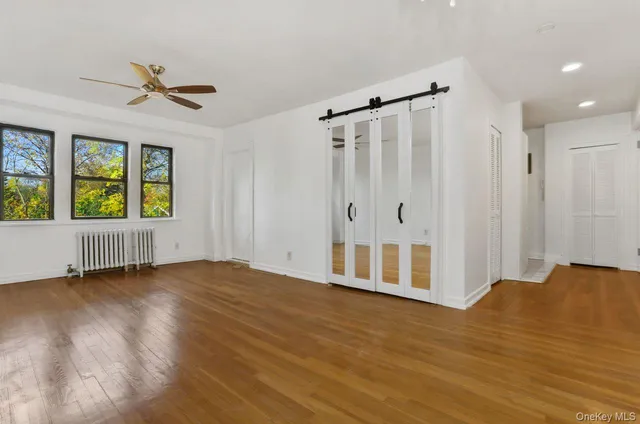 a view of an empty room with a window and wooden floor