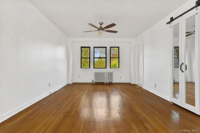 a view of an empty room with a window and wooden floor