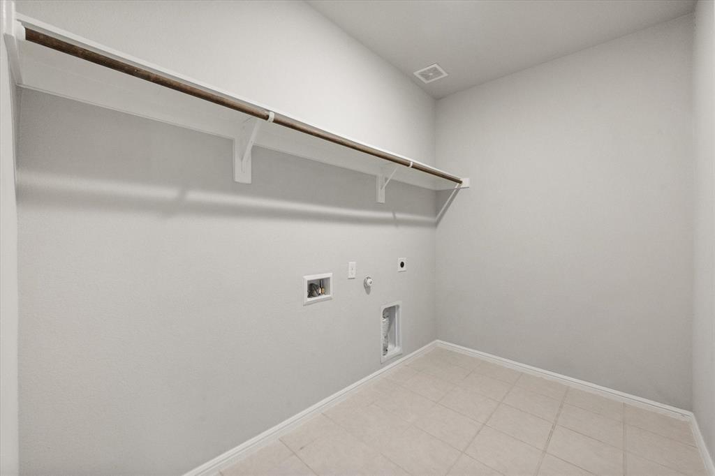 6910 Prairieside Trail Venus, TX 76084 - Photo 34 of 40 Laundry area featuring light-colored tile flooring, a wall-mounted shelf with a hanging rod, and utility hookups and room for a freezer!
