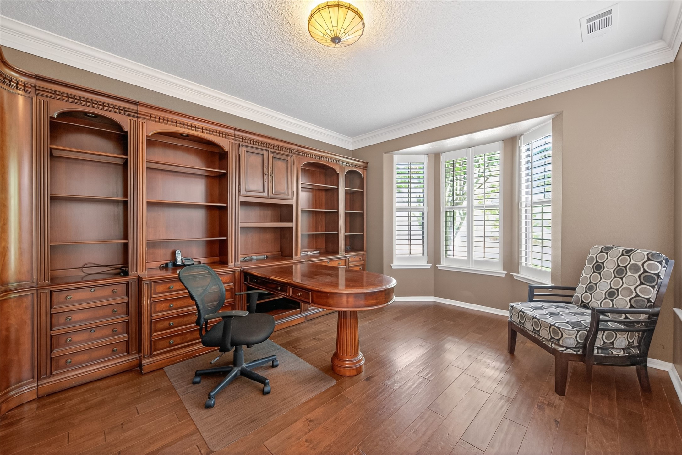 10 Mirror Ridge Drive The Woodlands, TX 77382 - Photo 9 of 48 Home office with front-facing bay windows, hardwood floors, and matching wooden shelving in a traditional style