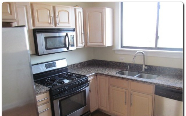 5655 North Spaulding Avenue, Unit 2W Chicago, IL 60659 - Photo 5 of 13 a kitchen with granite countertop white cabinets and stainless steel appliances