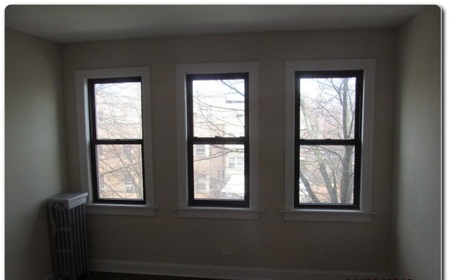 5655 North Spaulding Avenue, Unit 2W Chicago, IL 60659 - Photo 6 of 13 a view of an empty room with wooden floor and windows