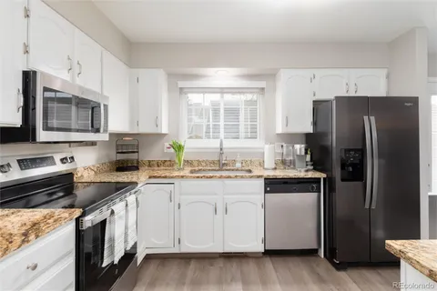 a kitchen with stainless steel appliances a refrigerator a stove a sink and white cabinets