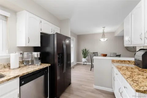a kitchen with granite countertop white cabinets and stainless steel appliances