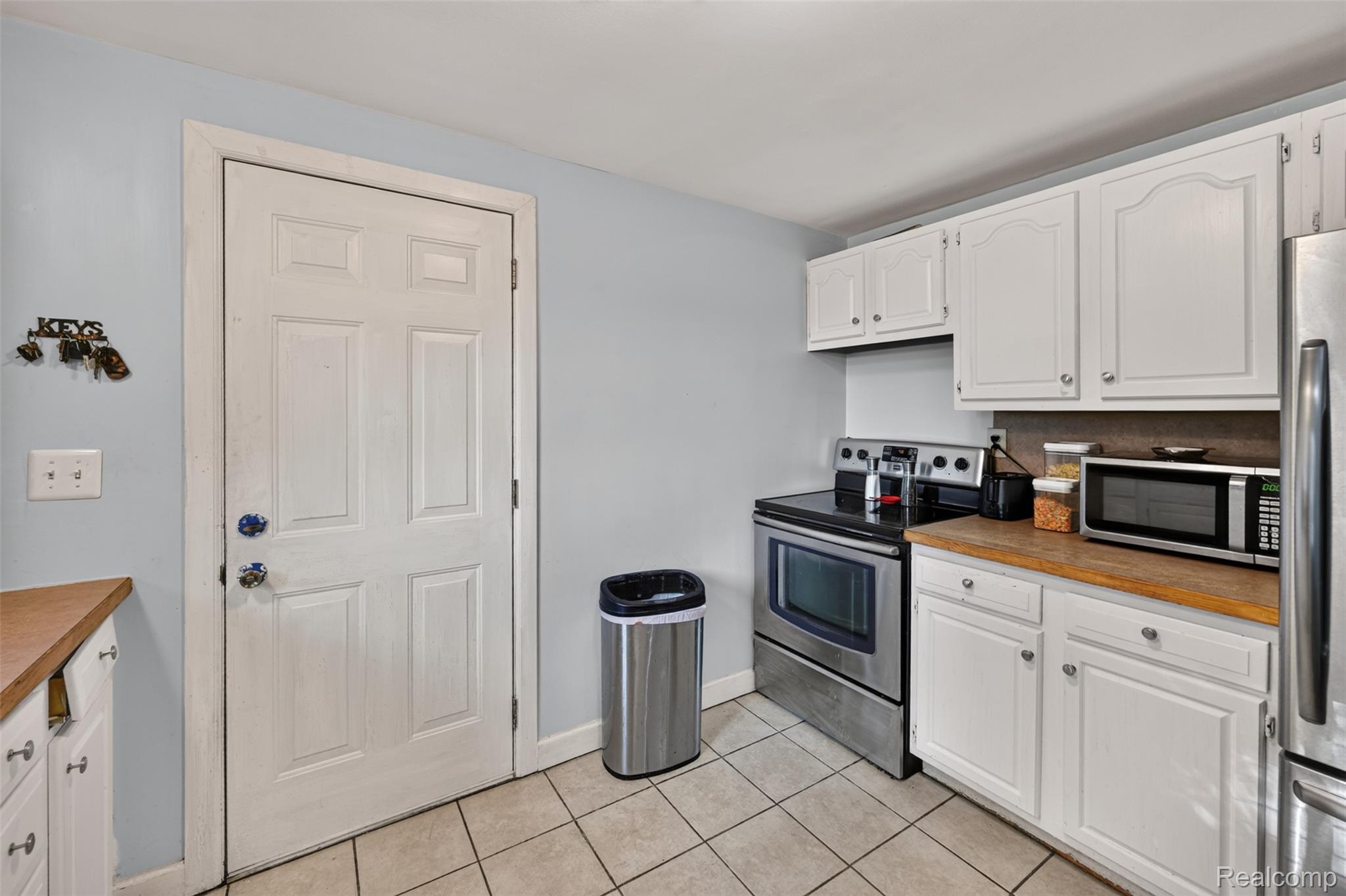 7369 North Webster Road Mount Morris, MI 48458 - Photo 28 of 56 White cabinetry with metal hardware, wood-finish countertops, stainless steel range, and tile flooring