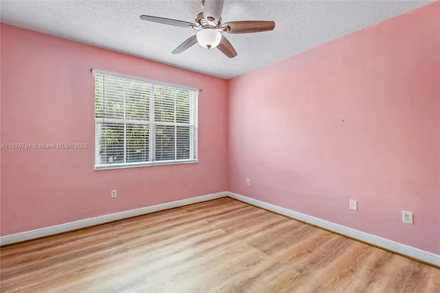 a view of an empty room with window and a chandelier fan