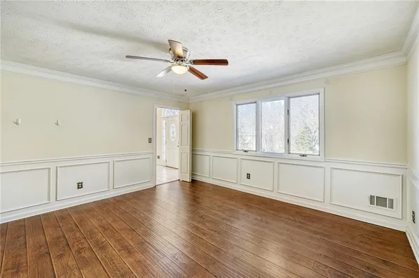 a view of an empty room with window and wooden floor