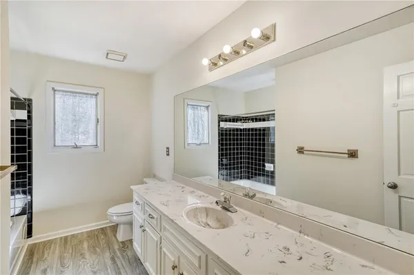 a bathroom with a granite countertop sink a toilet and a shower