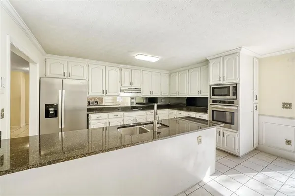 a kitchen with white cabinets a sink and white appliances