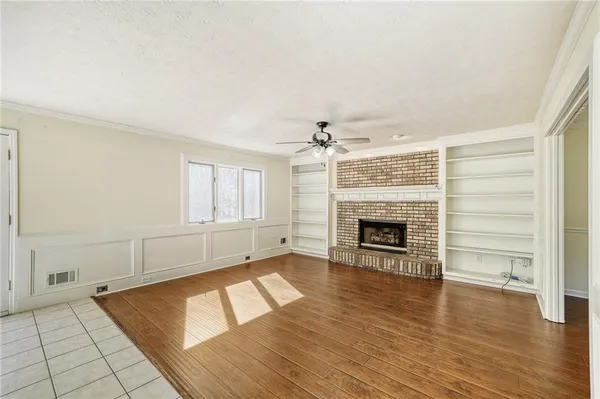 an empty room with wooden floor fireplace and windows