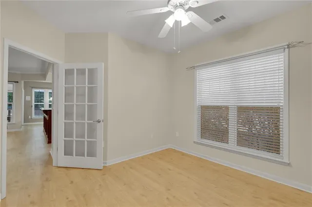a view of an empty room and kitchen view with wooden floor