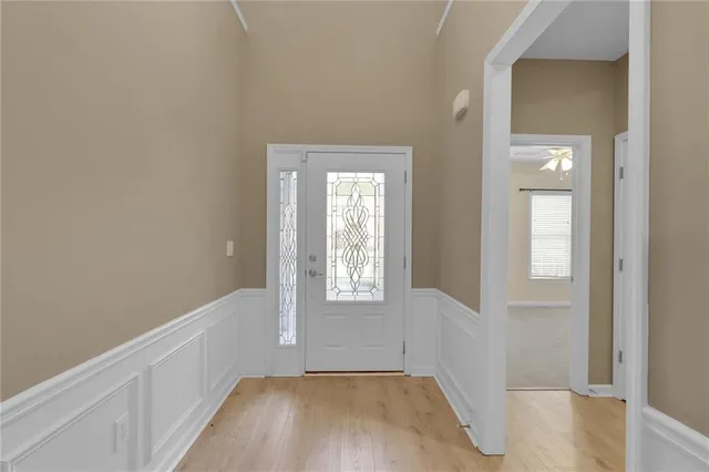 an empty room with chandelier fan and windows
