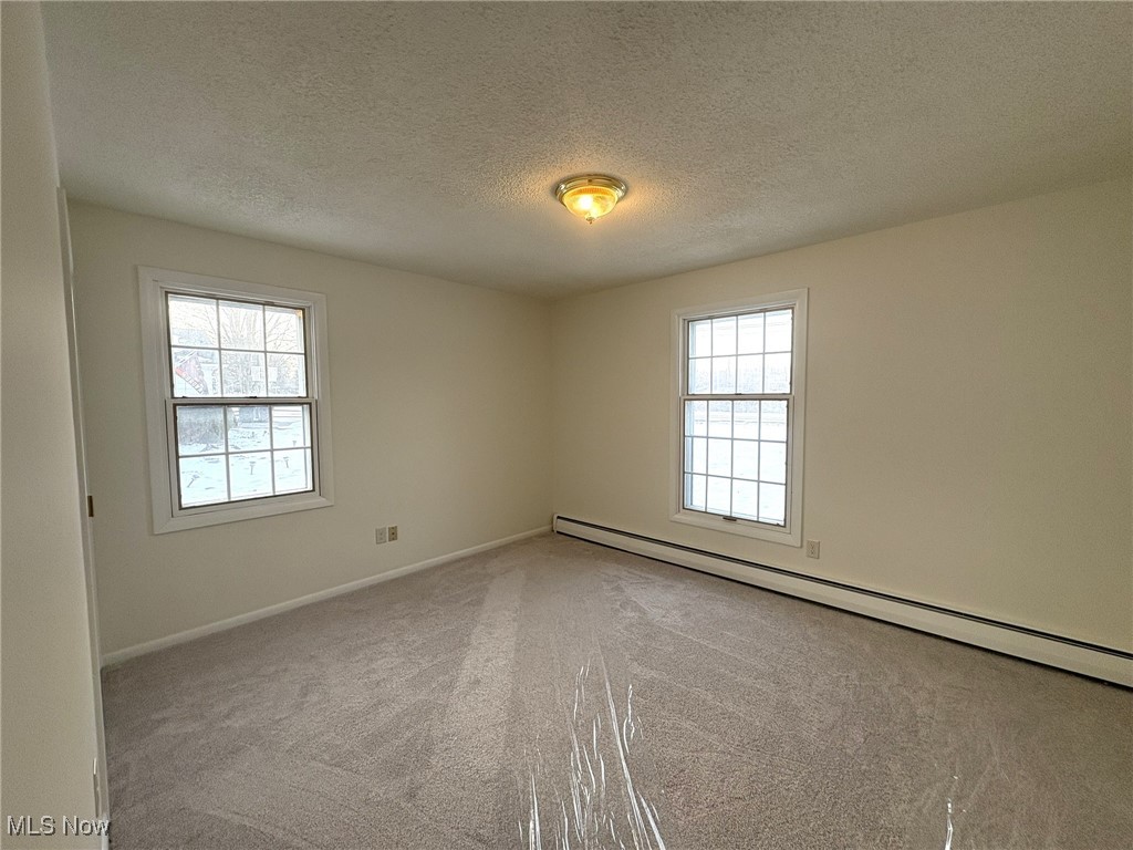39535 Butternut Ridge Road Elyria, OH 44035 - Photo 31 of 35 Empty room featuring a baseboard radiator, a textured ceiling, carpet floors, and healthy amount of natural light
