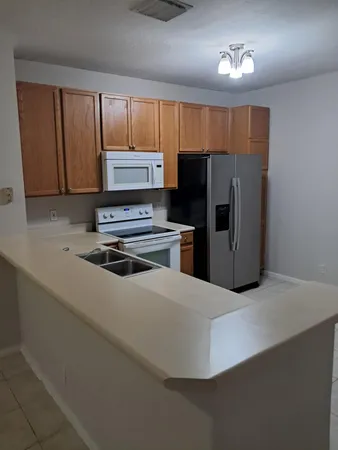 a kitchen with kitchen island a refrigerator and a stove top oven