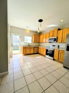 a large kitchen with stainless steel appliances a stove a sink dishwasher and a refrigerator with wooden floor