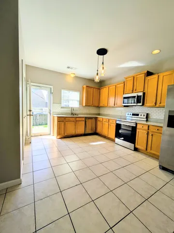 a large kitchen with stainless steel appliances a stove a sink dishwasher and a refrigerator with wooden floor