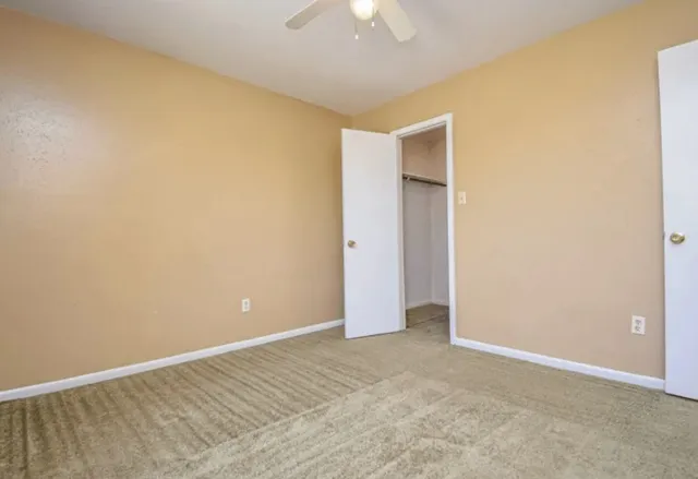 an empty room with a ceiling fan and a window