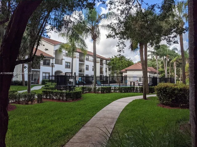 a view of a white house next to a yard with big trees