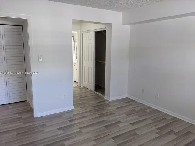 a view of an empty room with wooden floor and closet