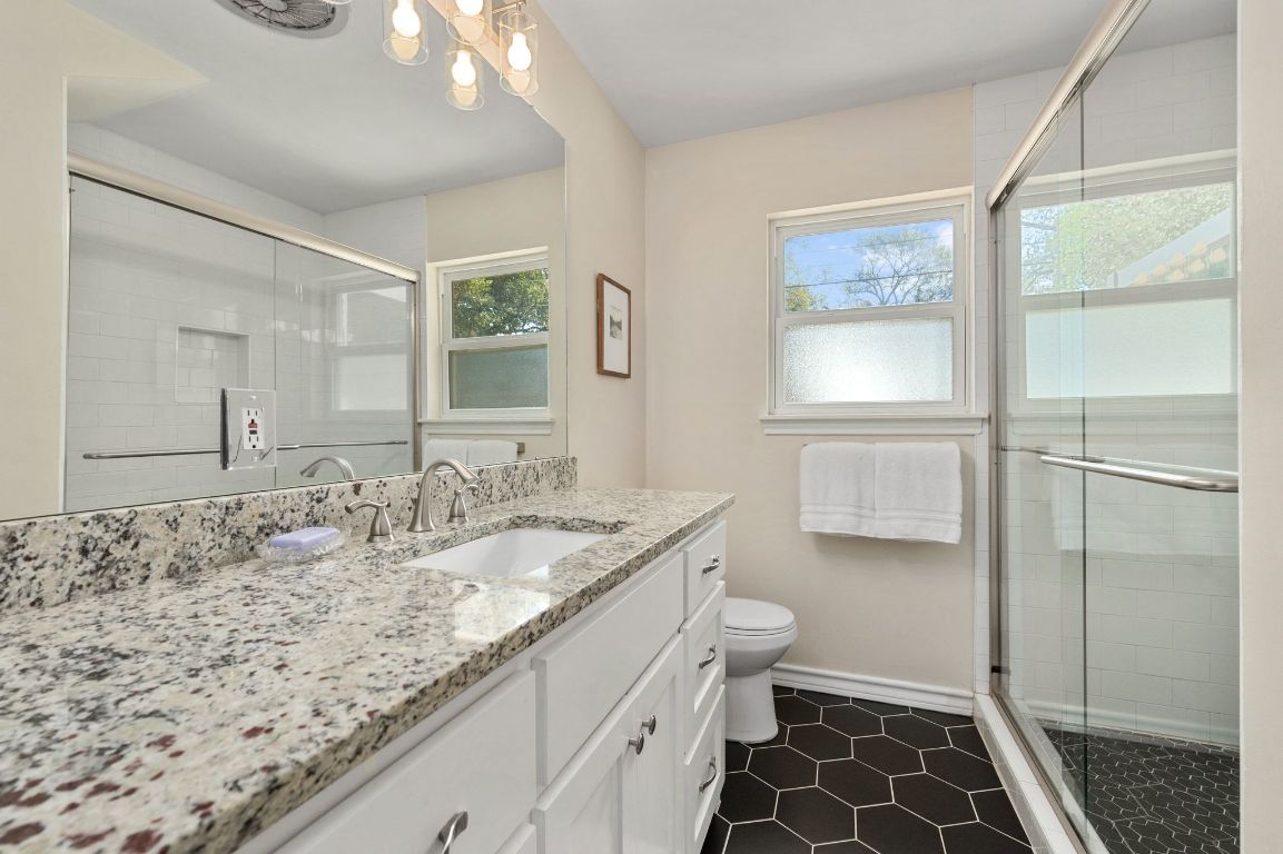 5605 Exeter Drive Austin, TX 78723 - Photo 21 of 32 a bathroom with a granite countertop sink a toilet and a mirror