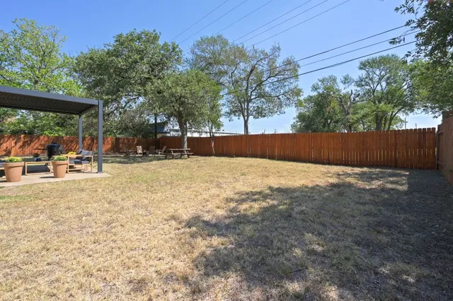 a backyard of a house with table and chairs under an umbrella