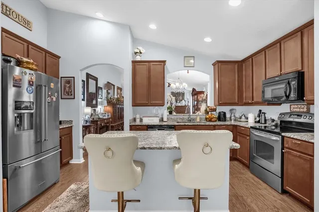 a kitchen with stainless steel appliances granite countertop a refrigerator a stove top oven a sink dishwasher and wooden cabinets