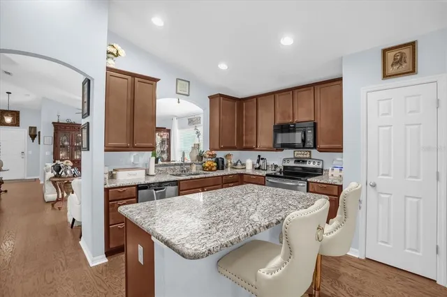 a kitchen with kitchen island granite countertop a sink stove and refrigerator