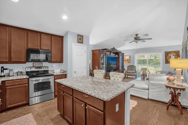 a kitchen with granite countertop kitchen island stainless steel appliances cabinets a sink and a stove