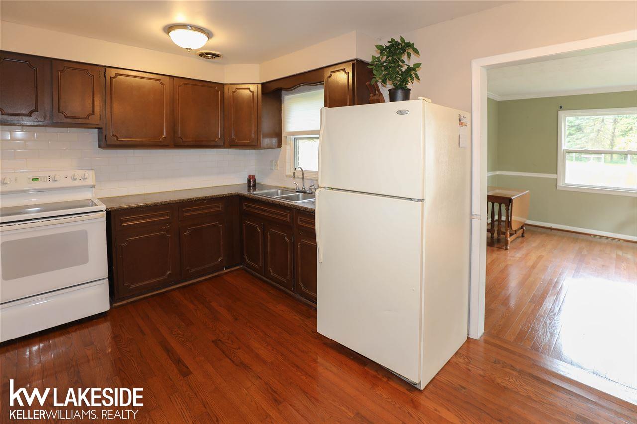 Kitchen w/ hardwood floors, granite counters, and tile backsplash, refrigerator and stove included.