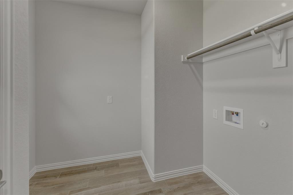 156 Oak Grv Way Springtown, TX 76082 - Photo 16 of 25 Dedicated utility space featuring wood-finish flooring, light gray walls, white baseboards, and a built-in hanging rod