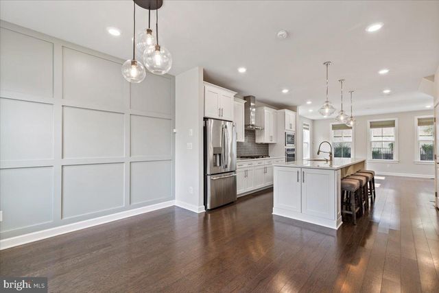 a kitchen with stainless steel appliances kitchen island granite countertop a refrigerator a stove a sink dishwasher and a dining table with wooden floor