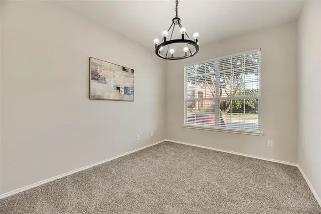 a view of an empty room with windows and chandelier