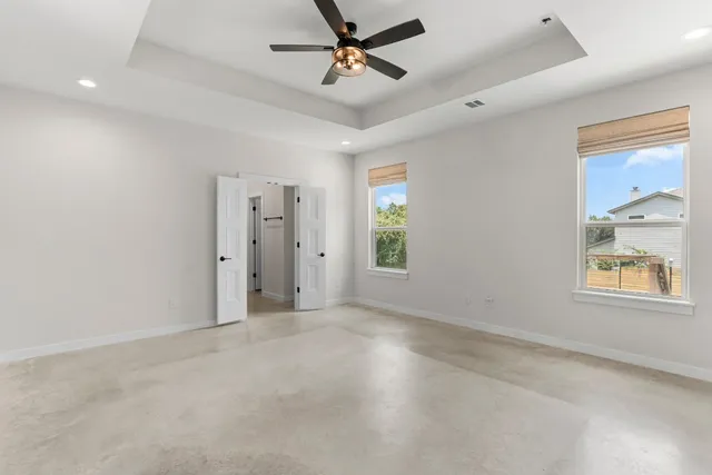 en empty room with windows and ceiling fan