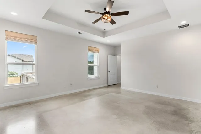 an empty room with windows and fan
