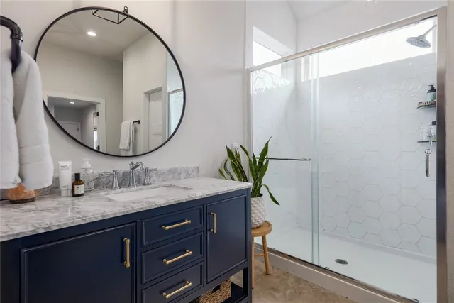 a bathroom with a granite countertop sink a mirror and shower