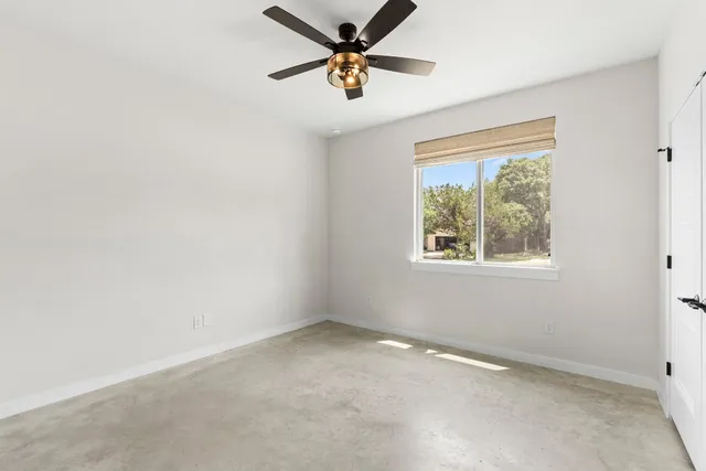 an empty room with a window and a fan