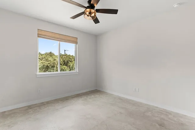 an empty room with a window and a ceiling fan