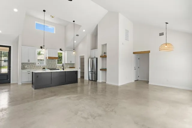 a view of kitchen with kitchen island stainless steel appliances sink cabinets and window