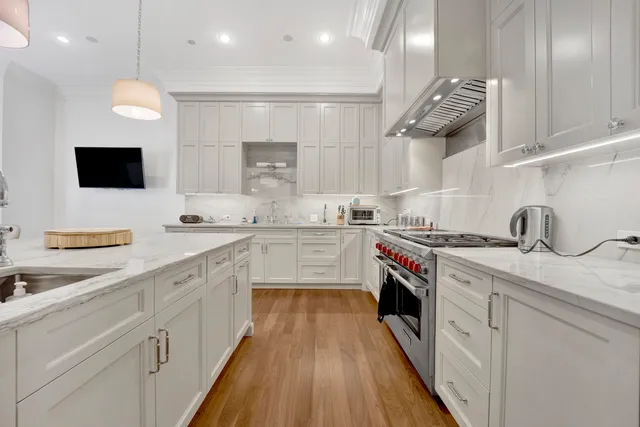 a large white kitchen with a white kitchen island and a wooden floor