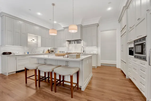 a kitchen with stainless steel appliances granite countertop a stove top oven a sink dishwasher a dining table and chairs with wooden floor