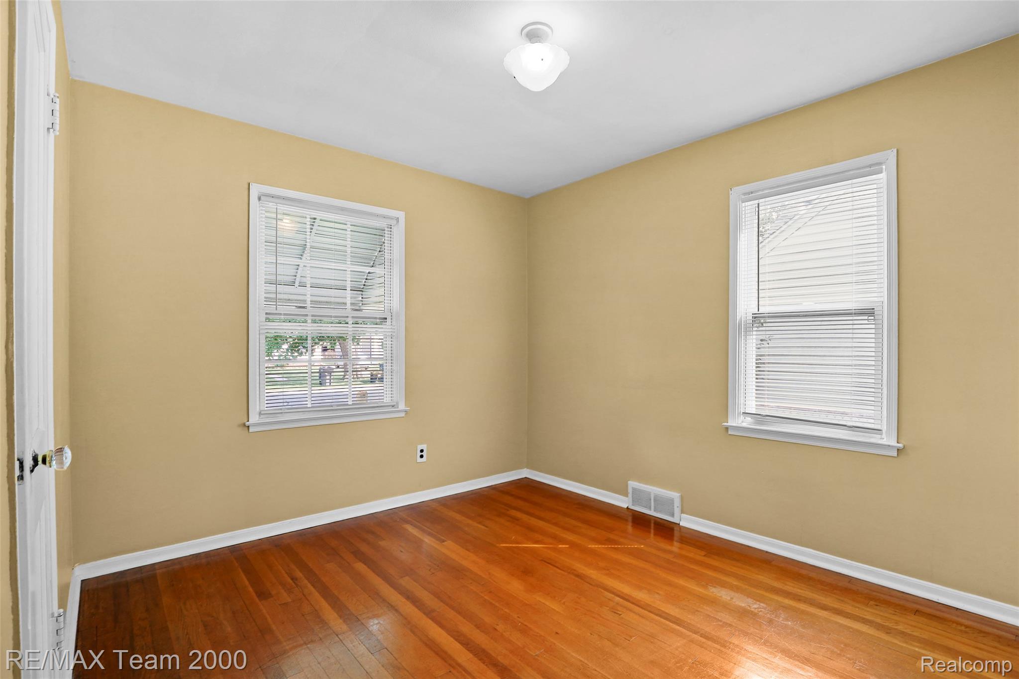 3130 Chestnut Street Dearborn, MI 48124 - Photo 15 of 30 Room featuring rich wood-finish flooring, light tan walls, and two windows with white blinds