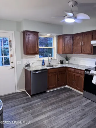 a kitchen with stainless steel appliances granite countertop a sink a stove a refrigerator cabinets and wooden floor