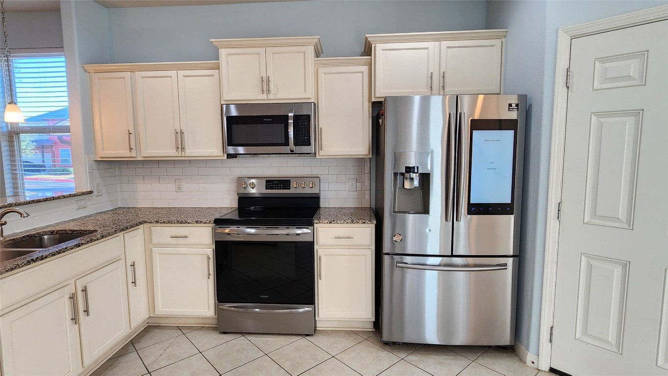 5432 Juniper Jct Lane Austin, TX 78744 - Photo 7 of 26 a kitchen with stainless steel appliances a refrigerator stove and white cabinets