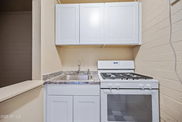 a kitchen with granite countertop a stove sink and cabinets